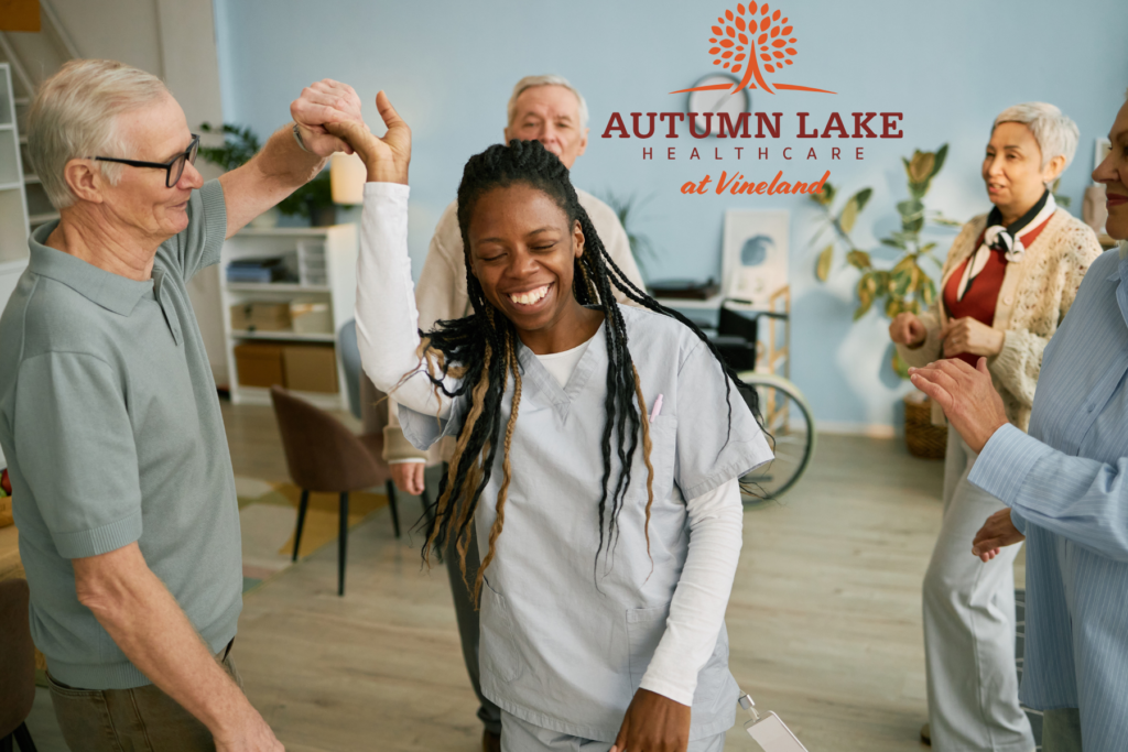 Nurse and senior resident dancing and smiling during an activity at a rehabilitation center.